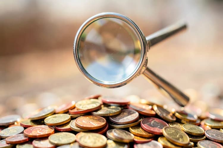 Uma lupa examinando moedas de dinheiro.