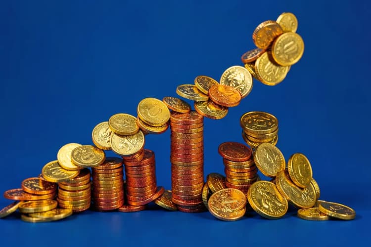 Gráfico de barras subindo com moedas de ouro caindo ao redor, em fundo azul.