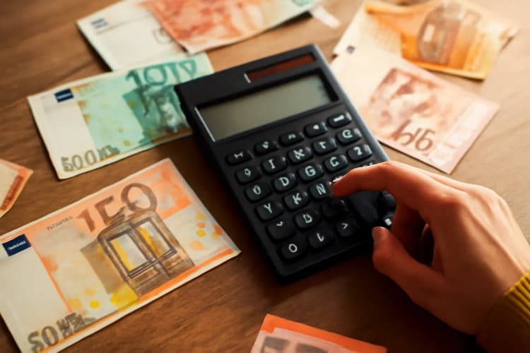 Como calcular o orçamento para tráfego pago? Mão com calculadora e notas.