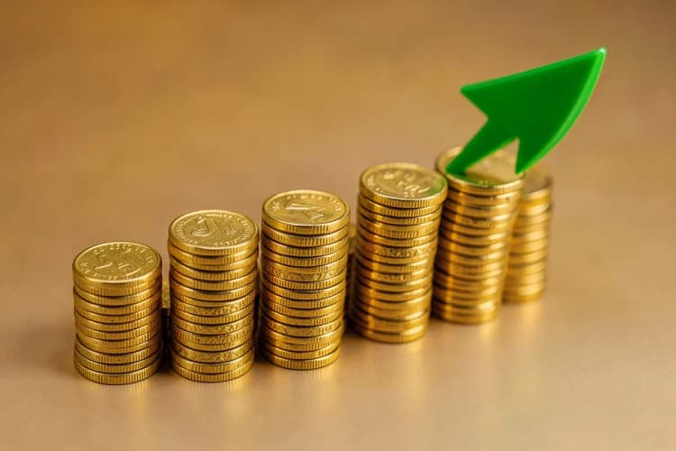 Um gráfico de barras ascendente feito de moedas de ouro empilhadas, com uma seta verde apontando para cima no canto superior direito.