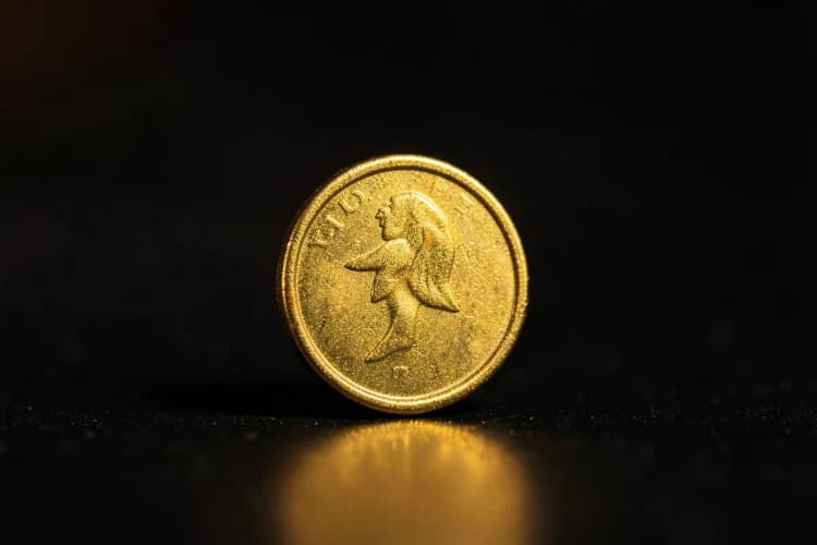Uma única moeda de ouro brilhante em um fundo escuro, close-up, luz de estúdio vindo da esquerda, sem ação.